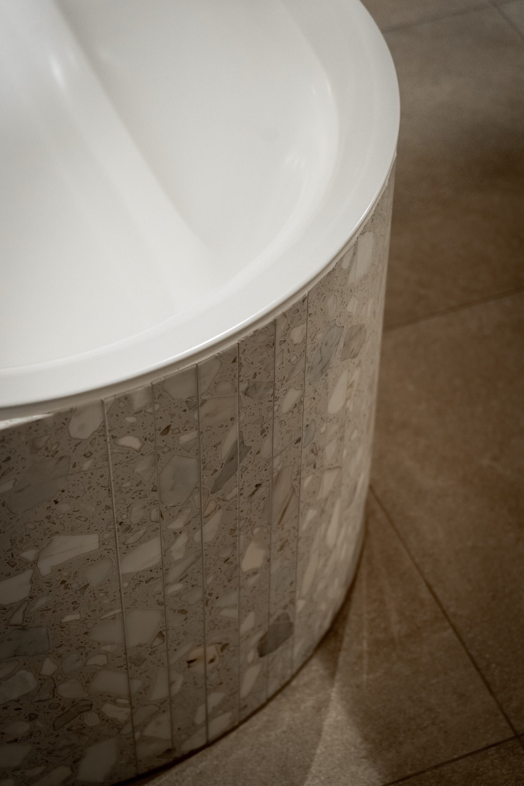 Curved terrazzo bath surround meeting the stone floor in Riverslate
