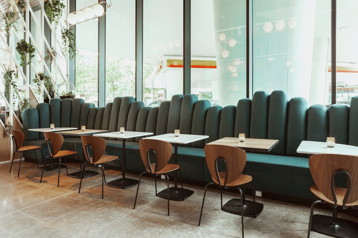 Green channel-tufted banquette with walnut chairs and marble tables at Fontein