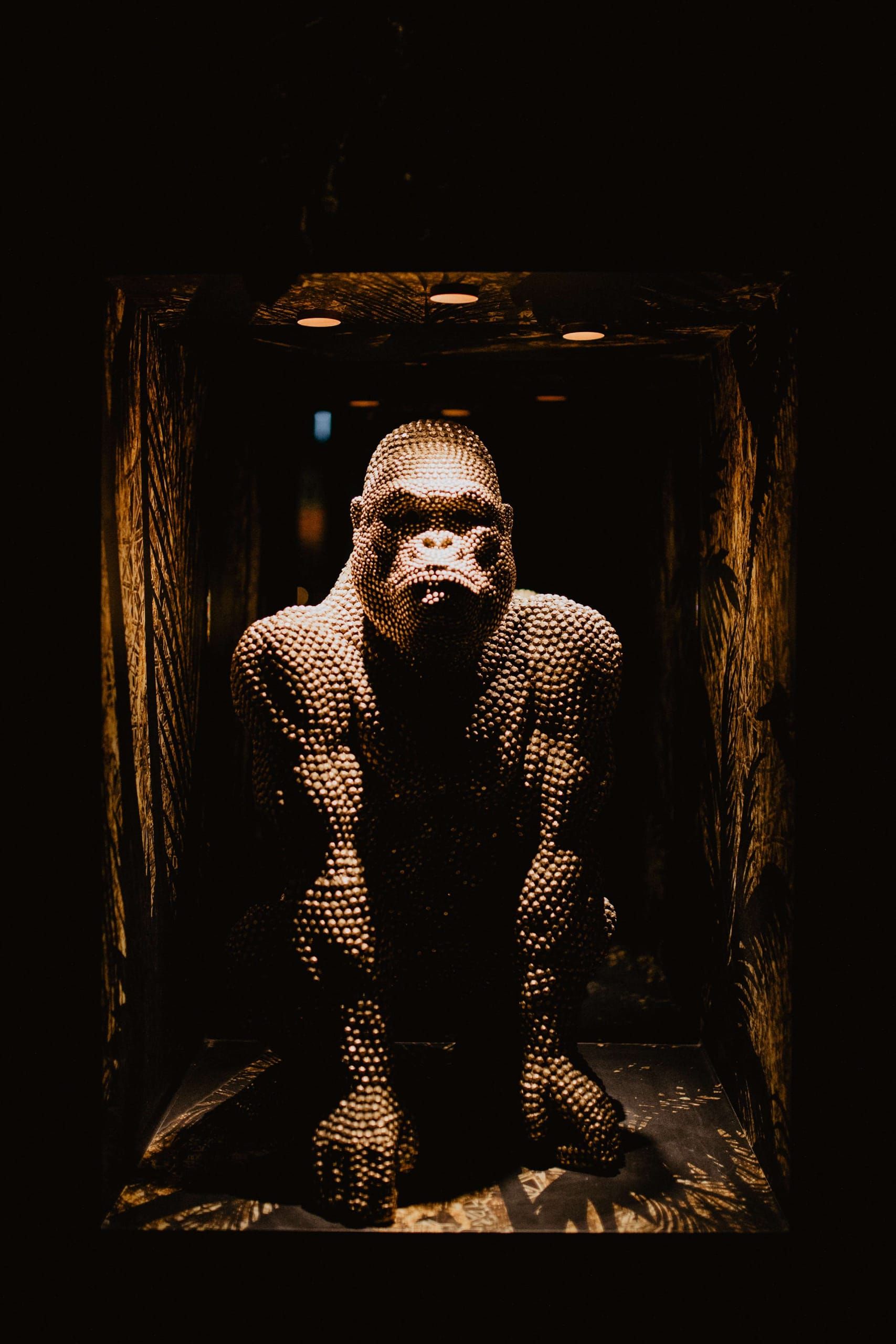 Studded gorilla sculpture lit inside a dark niche at Vandal