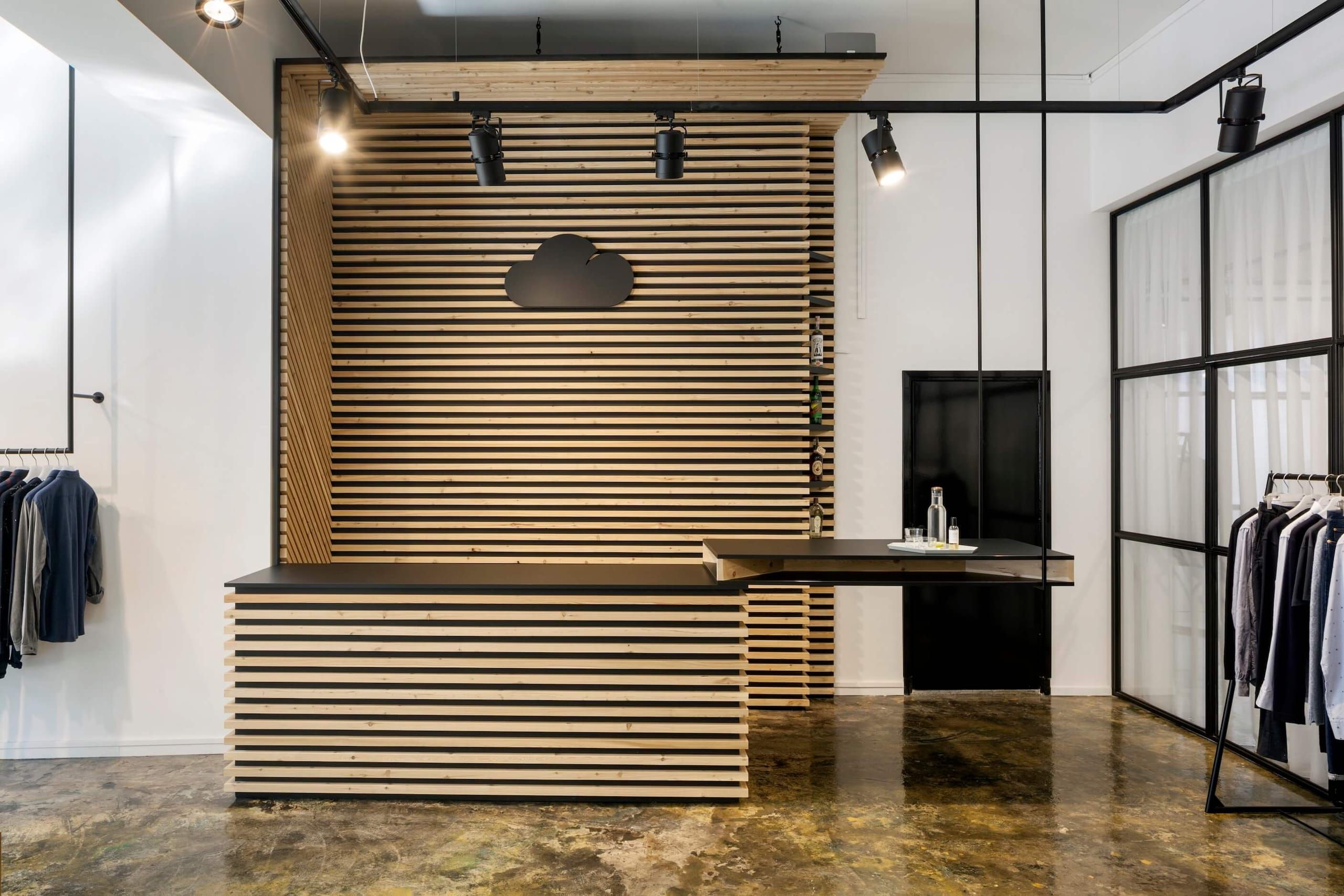 Slatted oak reception counter with a cloud logo and a black steel glass partition