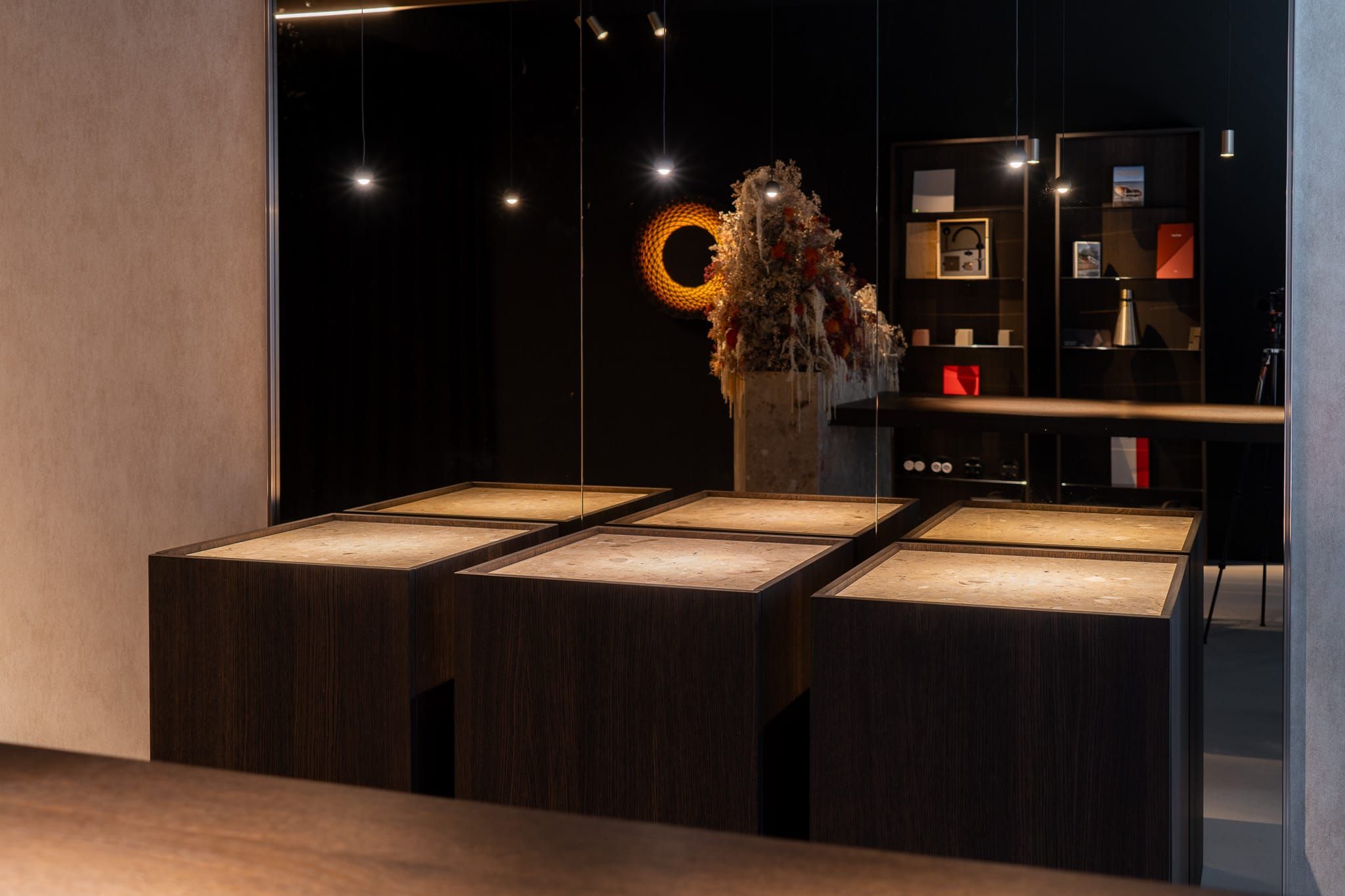 Dark oak display plinths with lit stone tops reflected in a mirror