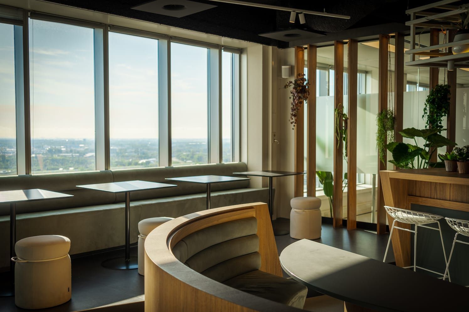 Window seating with round stools, low tables and a curved wooden booth