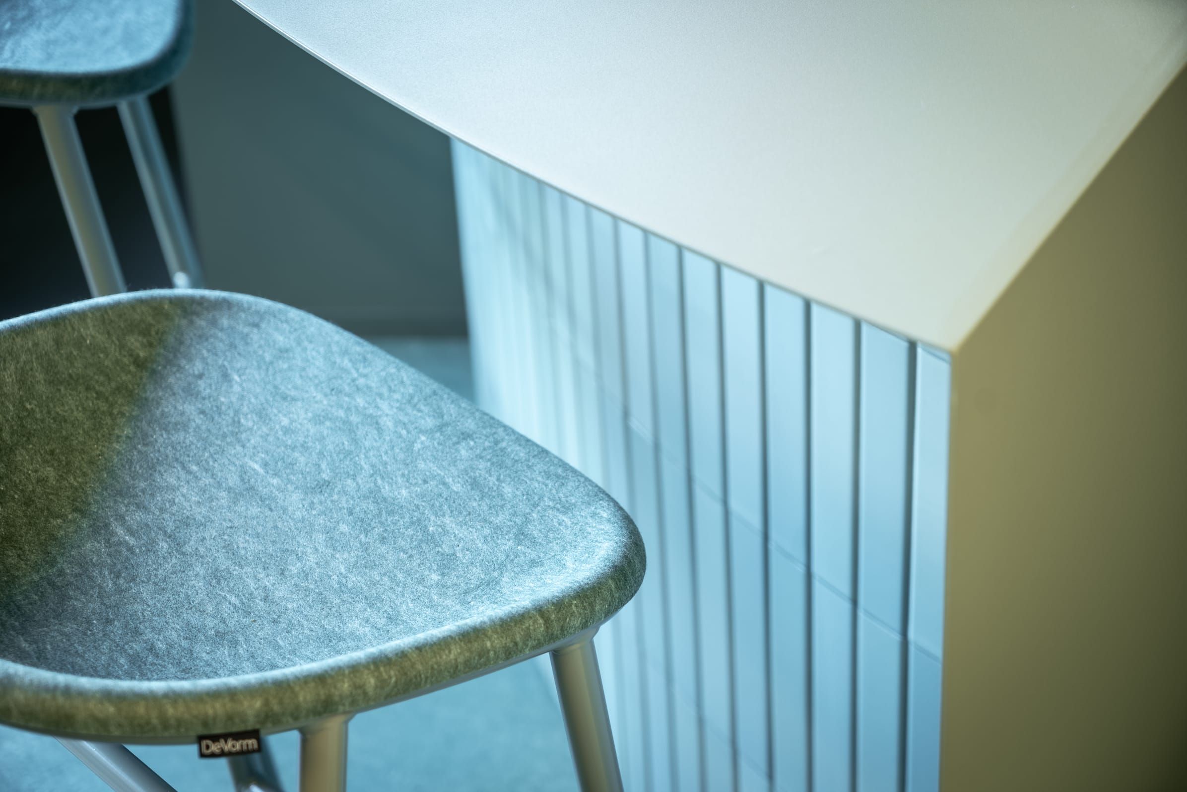 Close-up of a felt bar stool seat beside a pale green tiled counter