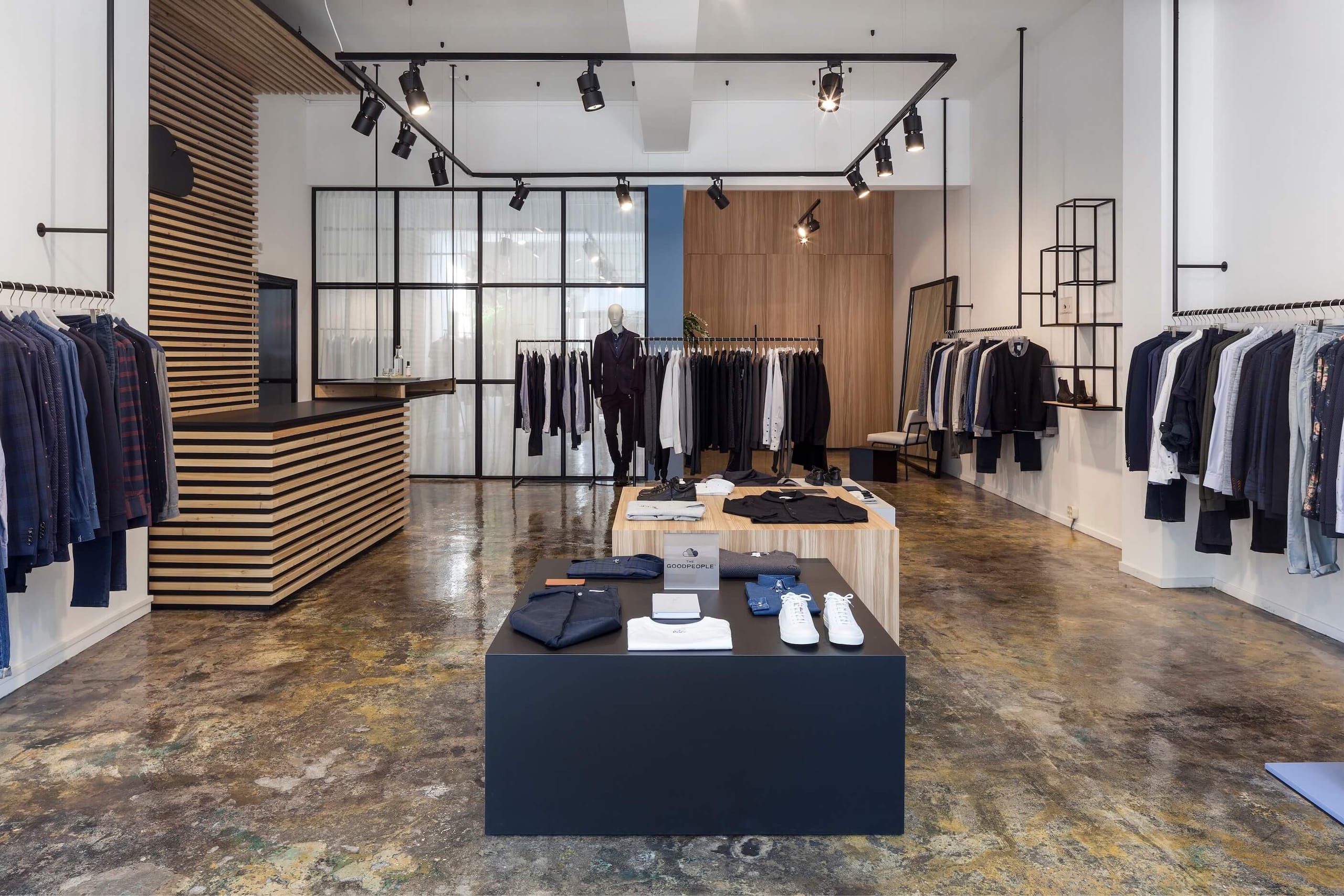 Store interior with black display table, rails of menswear and track spotlights