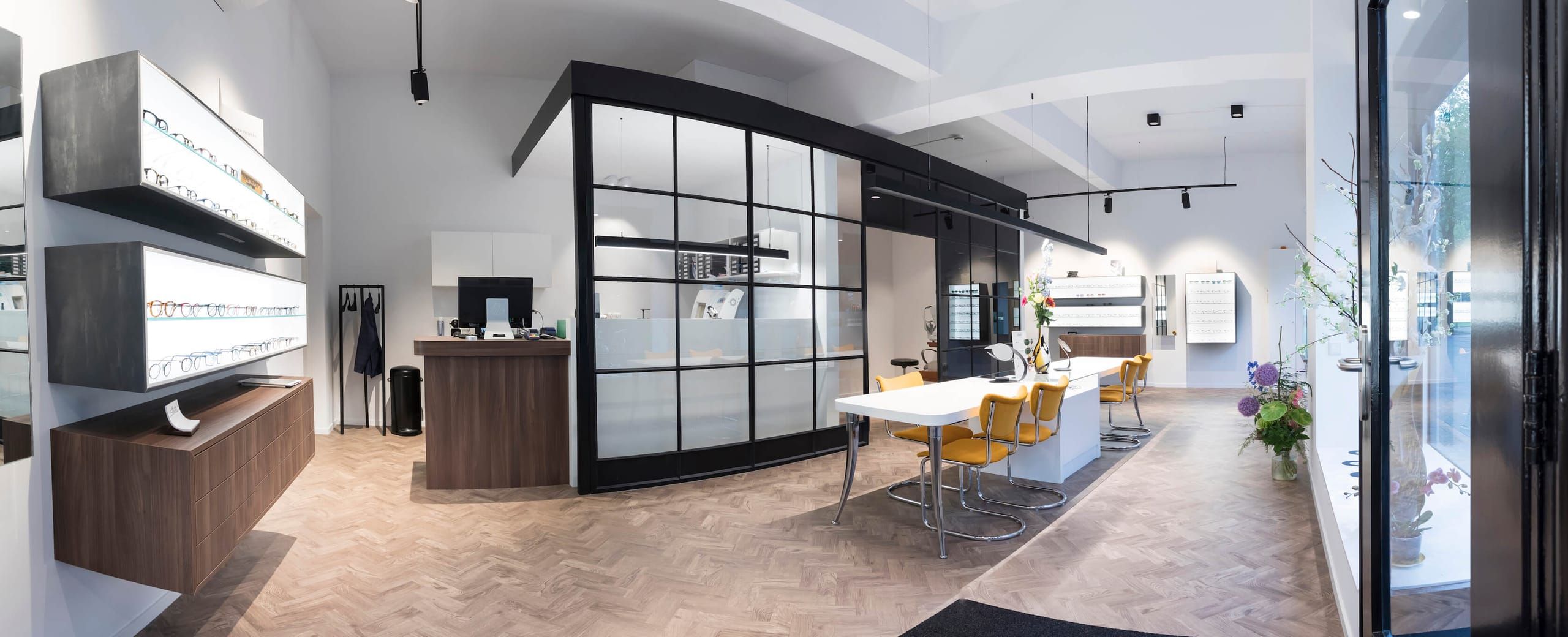 Wide view of the optician with eyewear wall, reception desk and herringbone floor