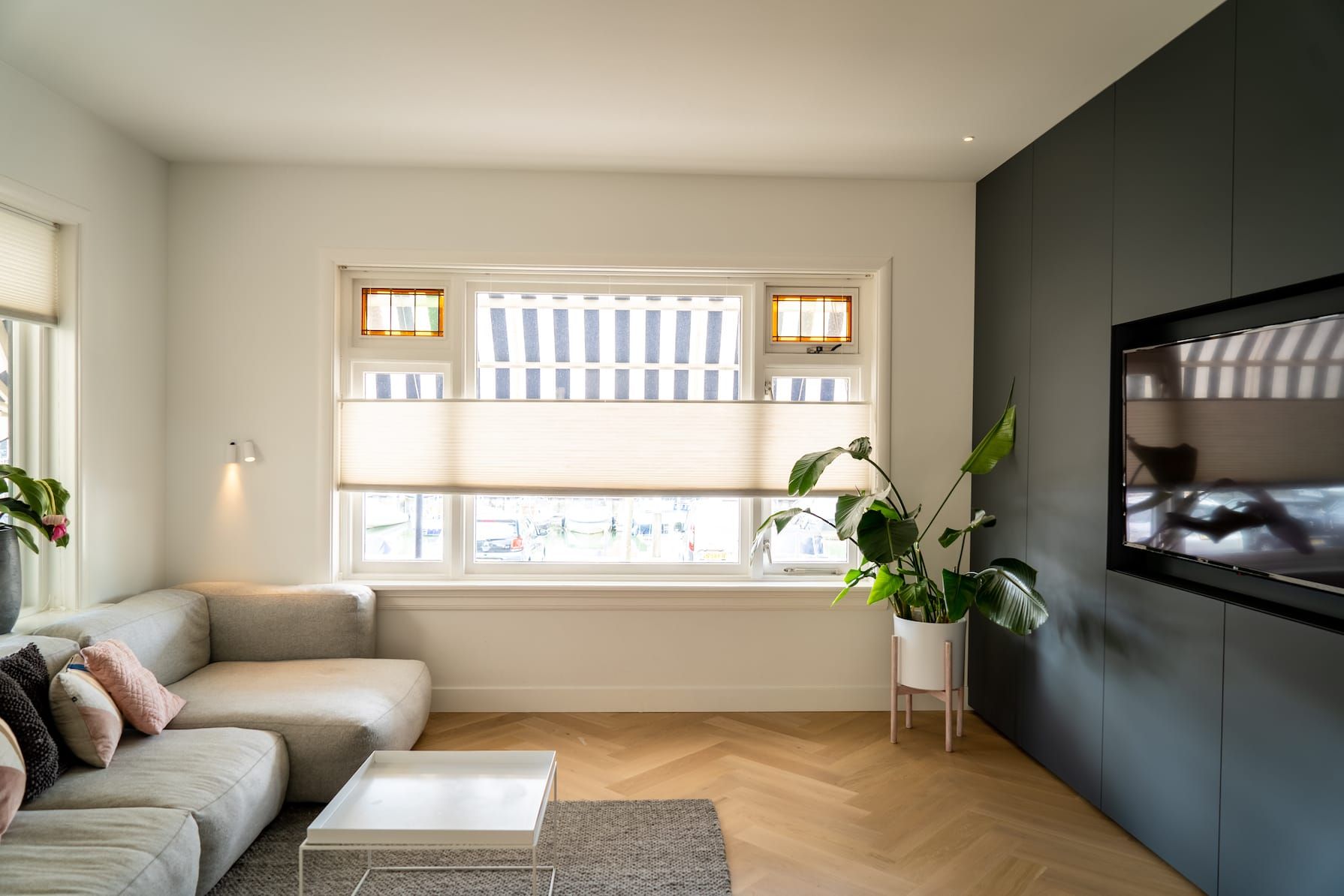 Living room with grey sofa, black cabinet wall and herringbone oak floor