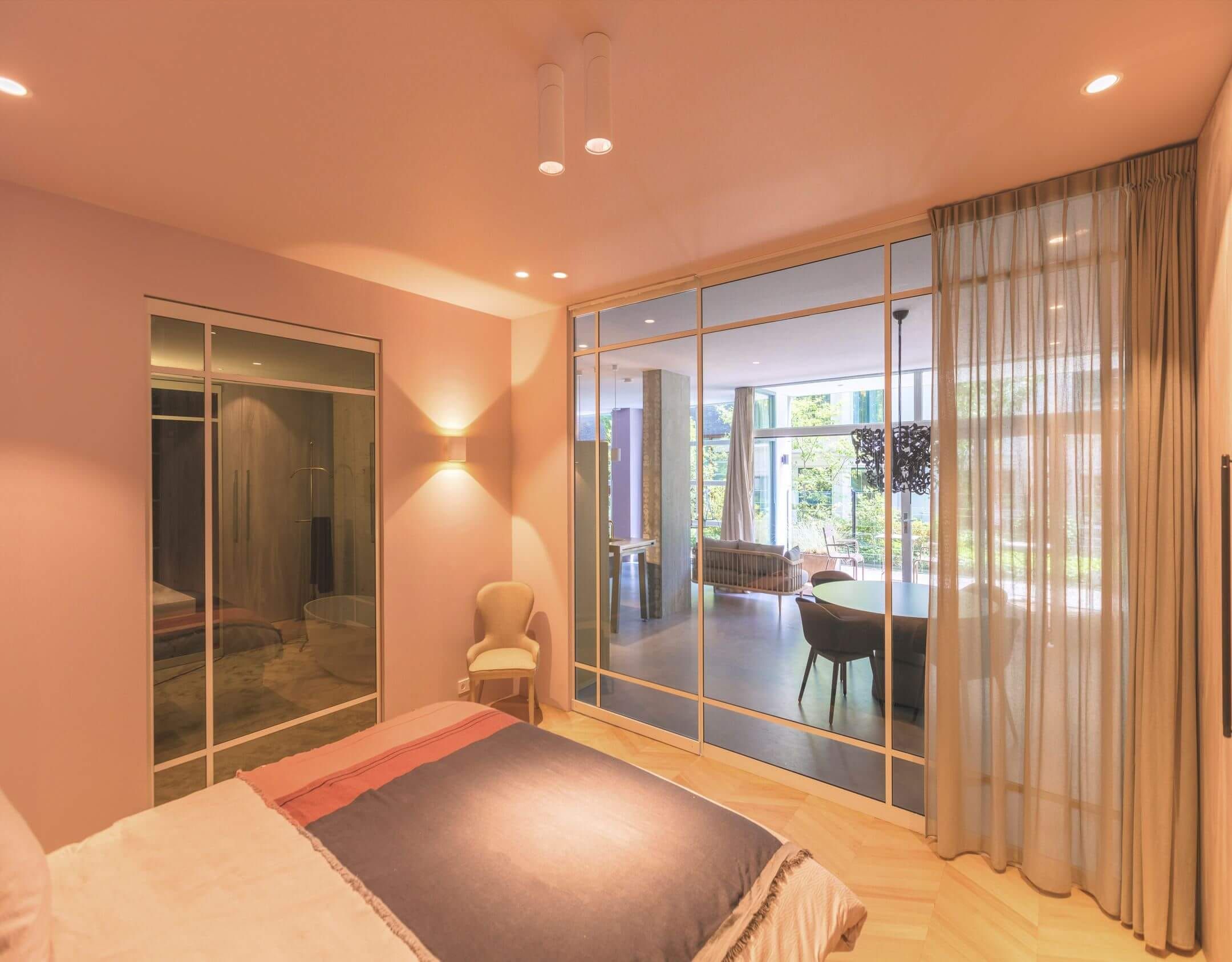 Bedroom with glass partition to the dining area, sheer curtain and herringbone floor