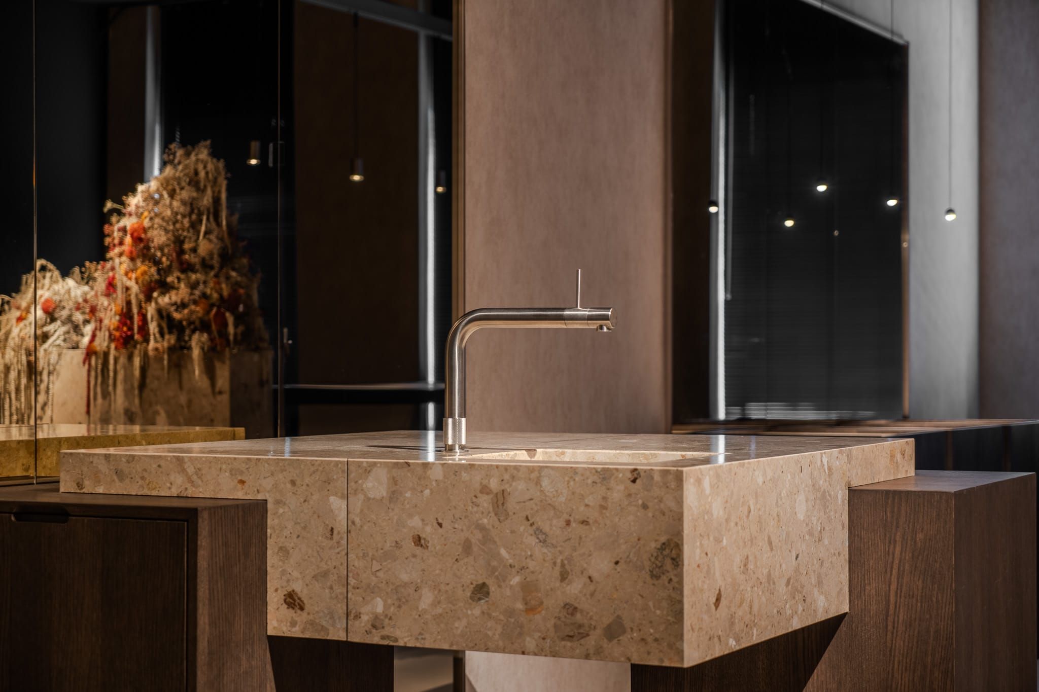 Terrazzo sink block with a slim chrome tap beside a dried flower arrangement