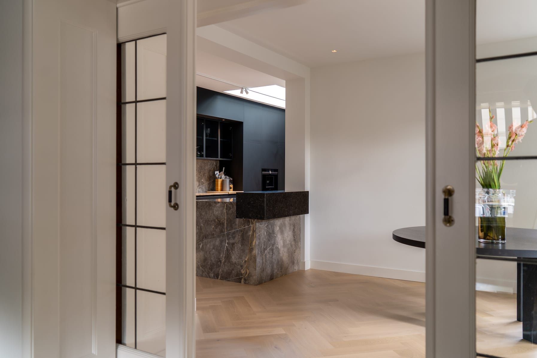 View through white sliding doors to the kitchen island and dining table