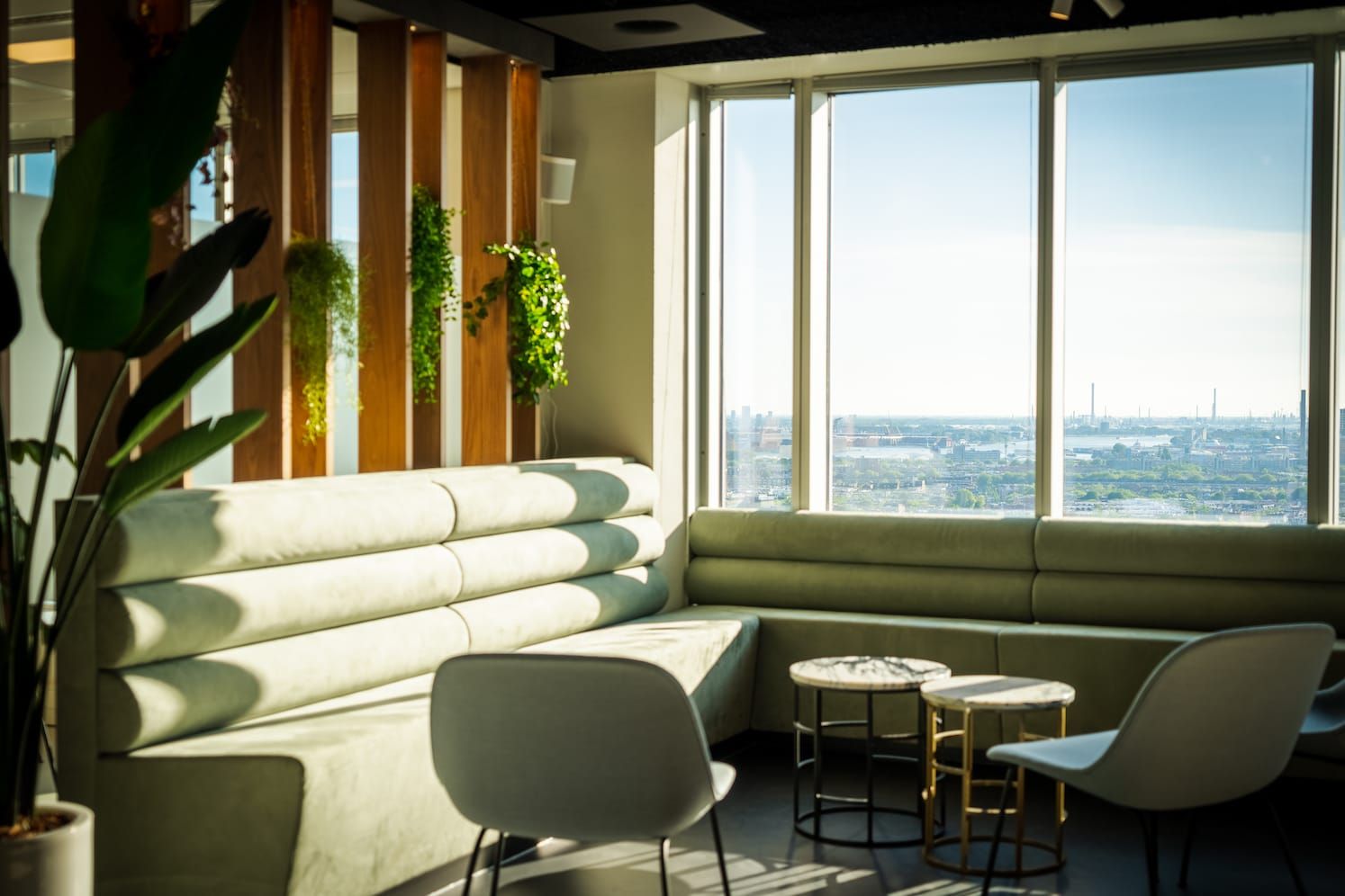 Pale green banquette sofas and marble side tables with a view over the city
