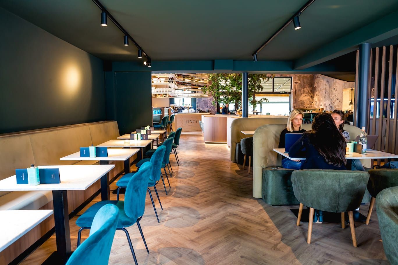 Dining area with teal chairs, white tables and herringbone floor at Finca