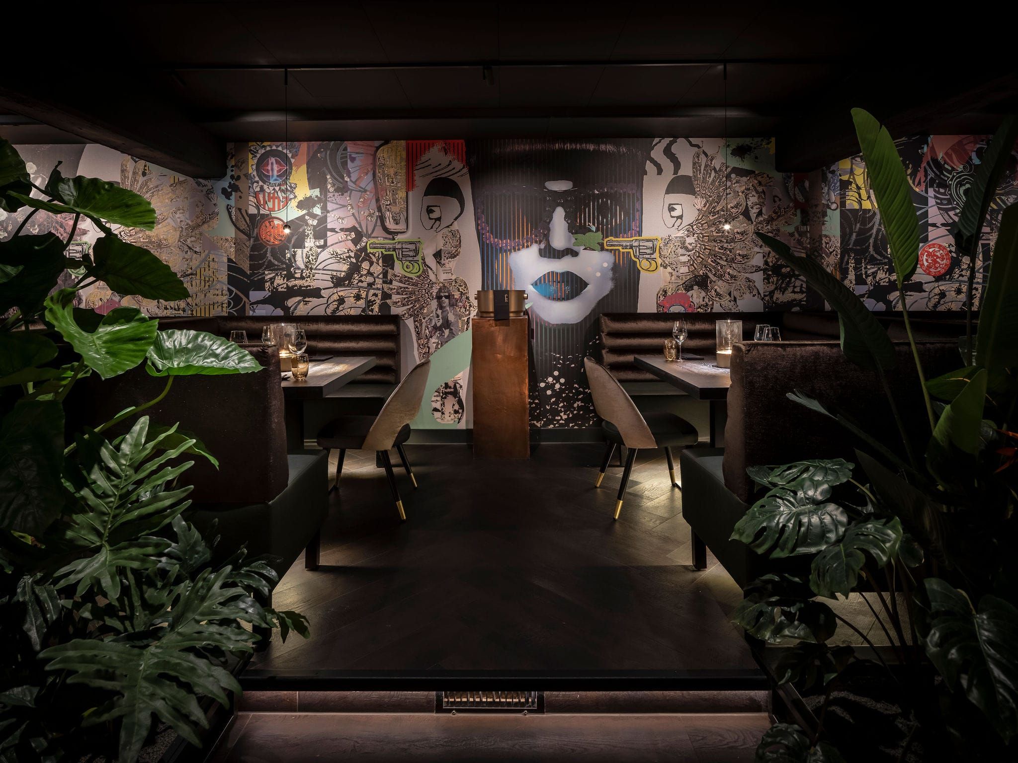 Graphic pop-art mural wall with plants and tables on a dark herringbone floor