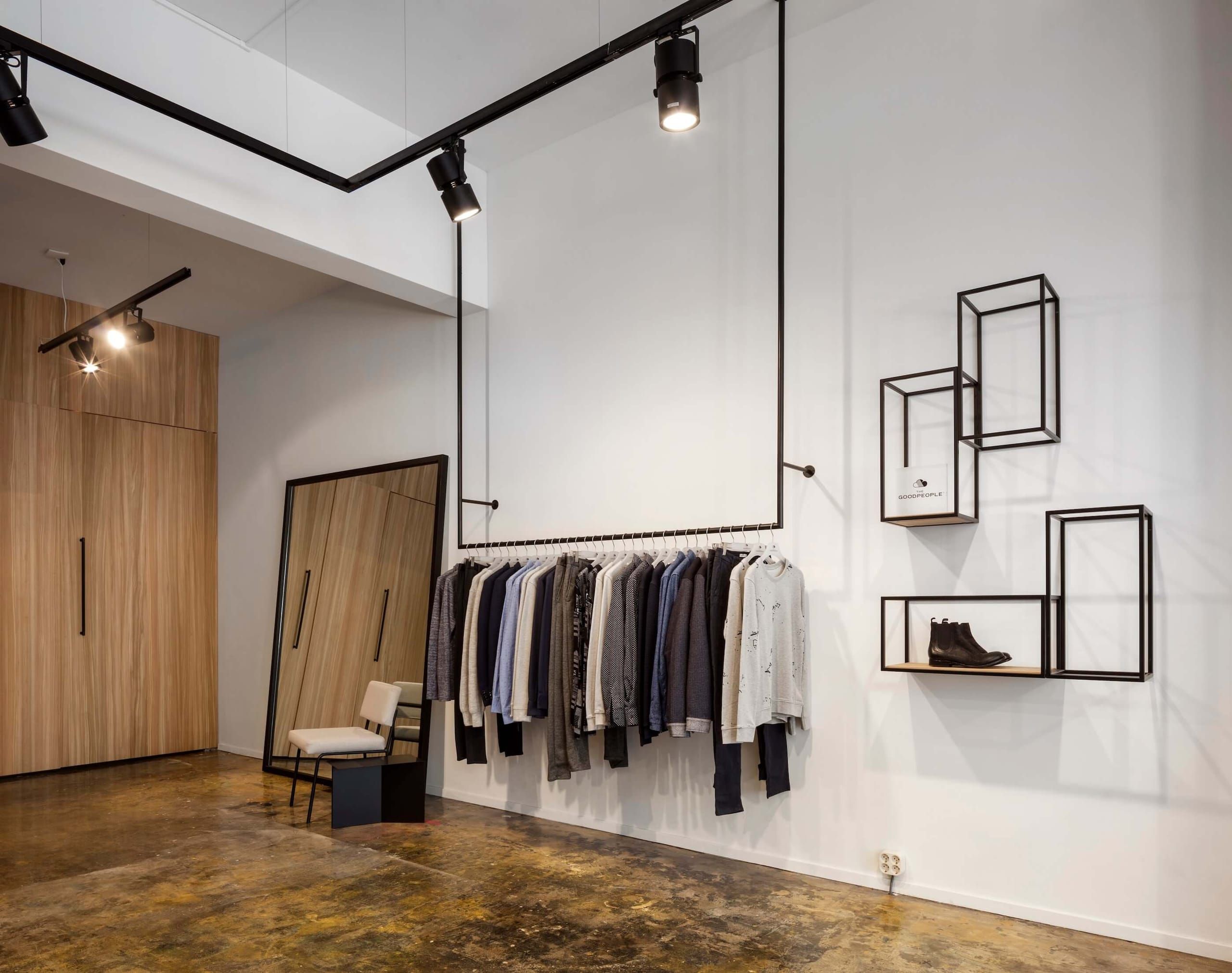 Black rail with hanging menswear, wire frame shelves and a leaning floor mirror
