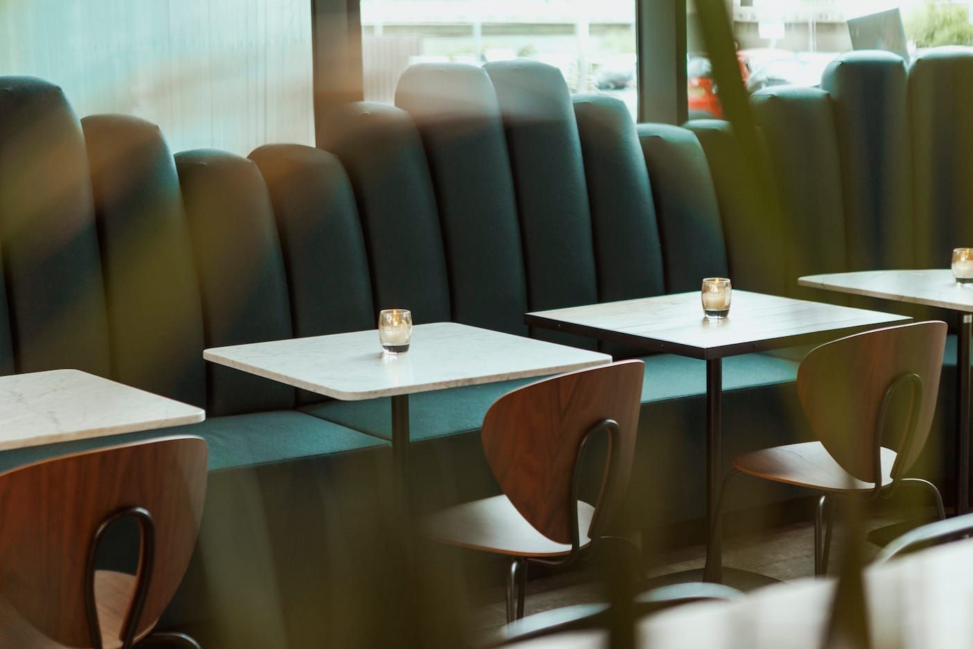 Banquette seating with marble tables and glass candle holders by the windows