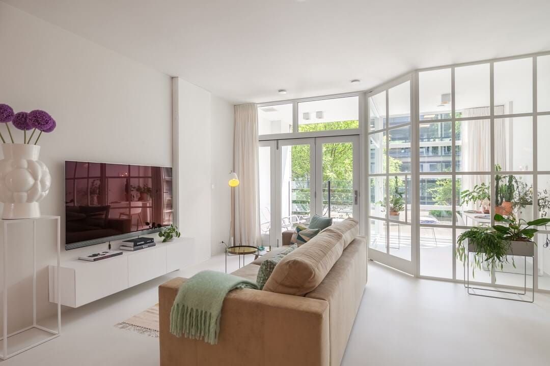 Living room with television unit, glass steel partition and pale sofa
