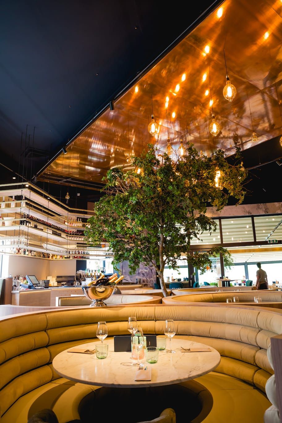 Round banquette, champagne cooler and tree beneath the copper ceiling at Finca