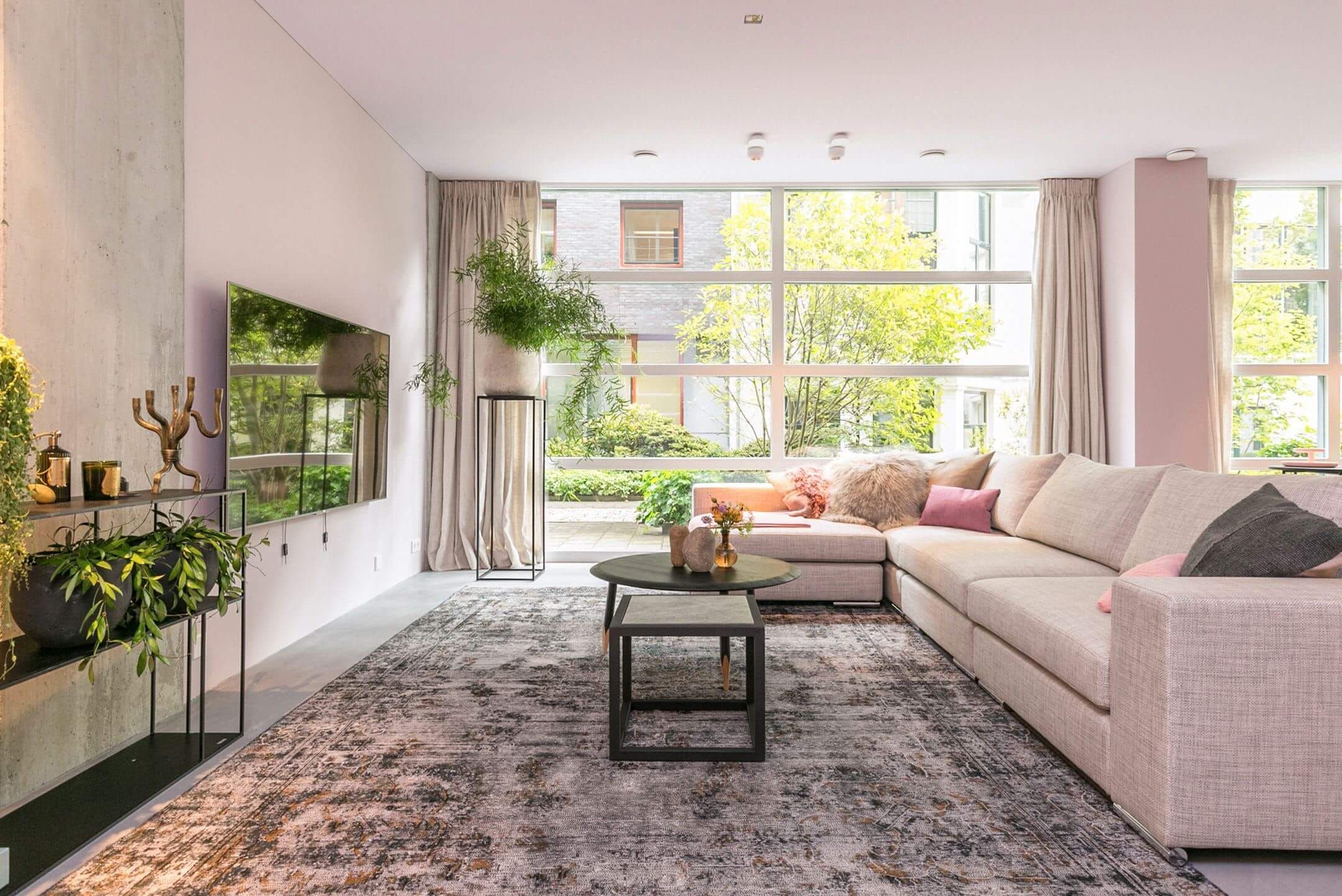 Living room with beige sofa, large rug and floor-to-ceiling courtyard windows