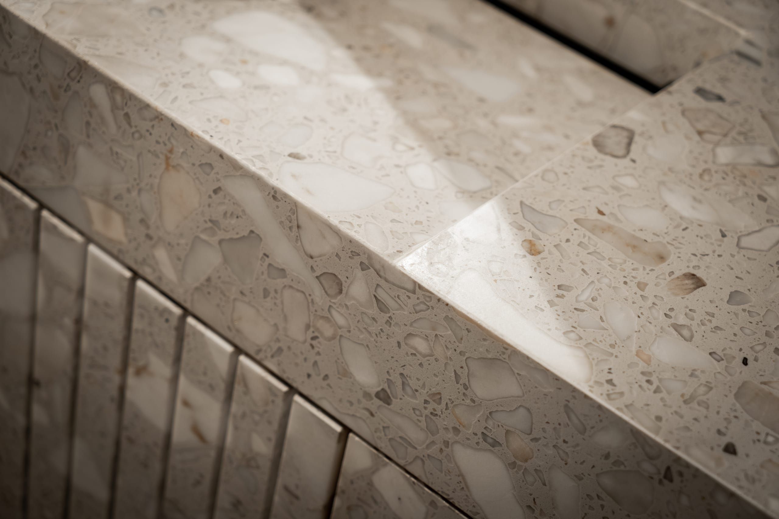 Close view of the terrazzo vanity edge above fluted drawer fronts