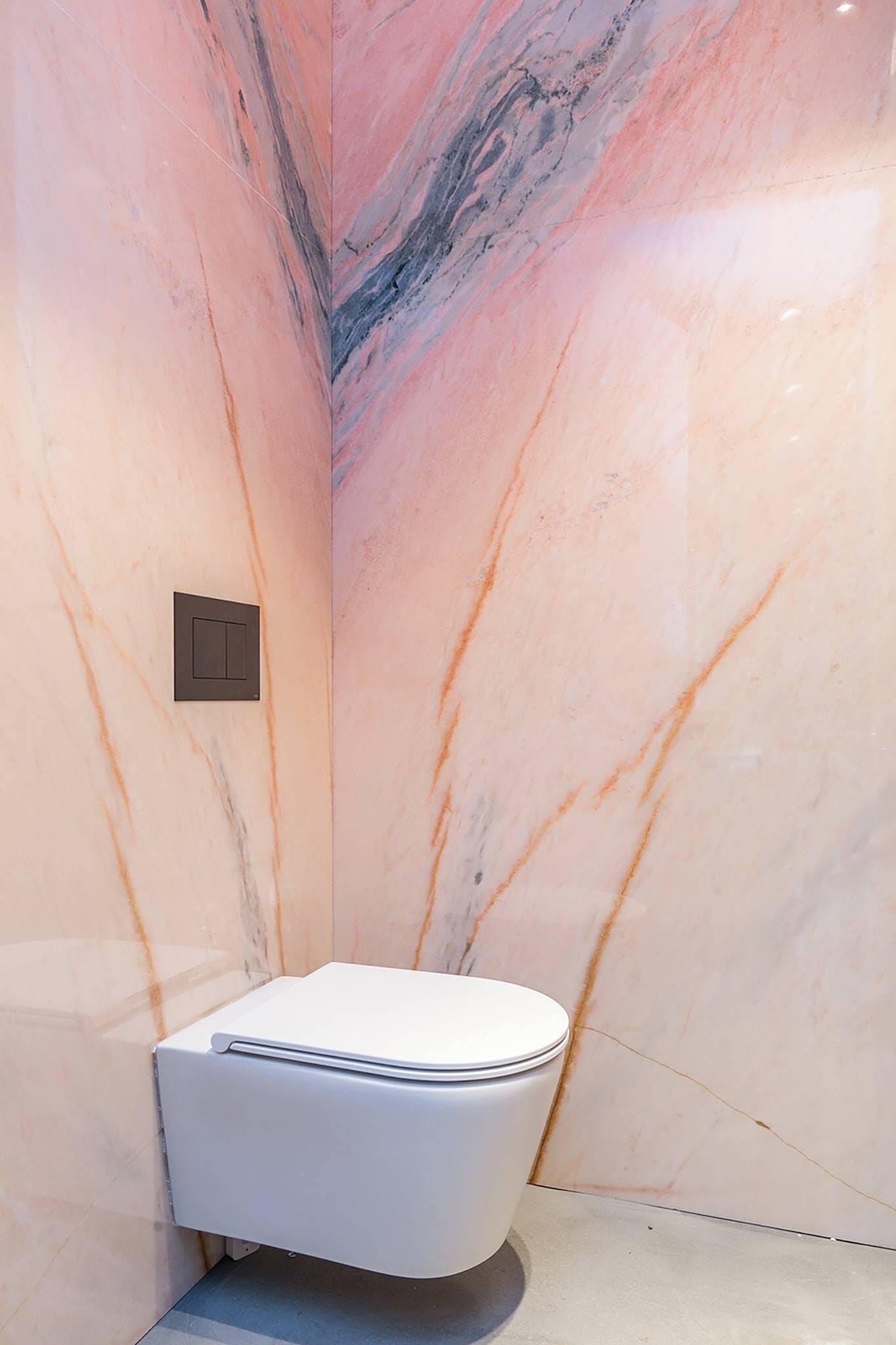 Wall hung toilet against pink veined stone slabs in the Stardust cloakroom