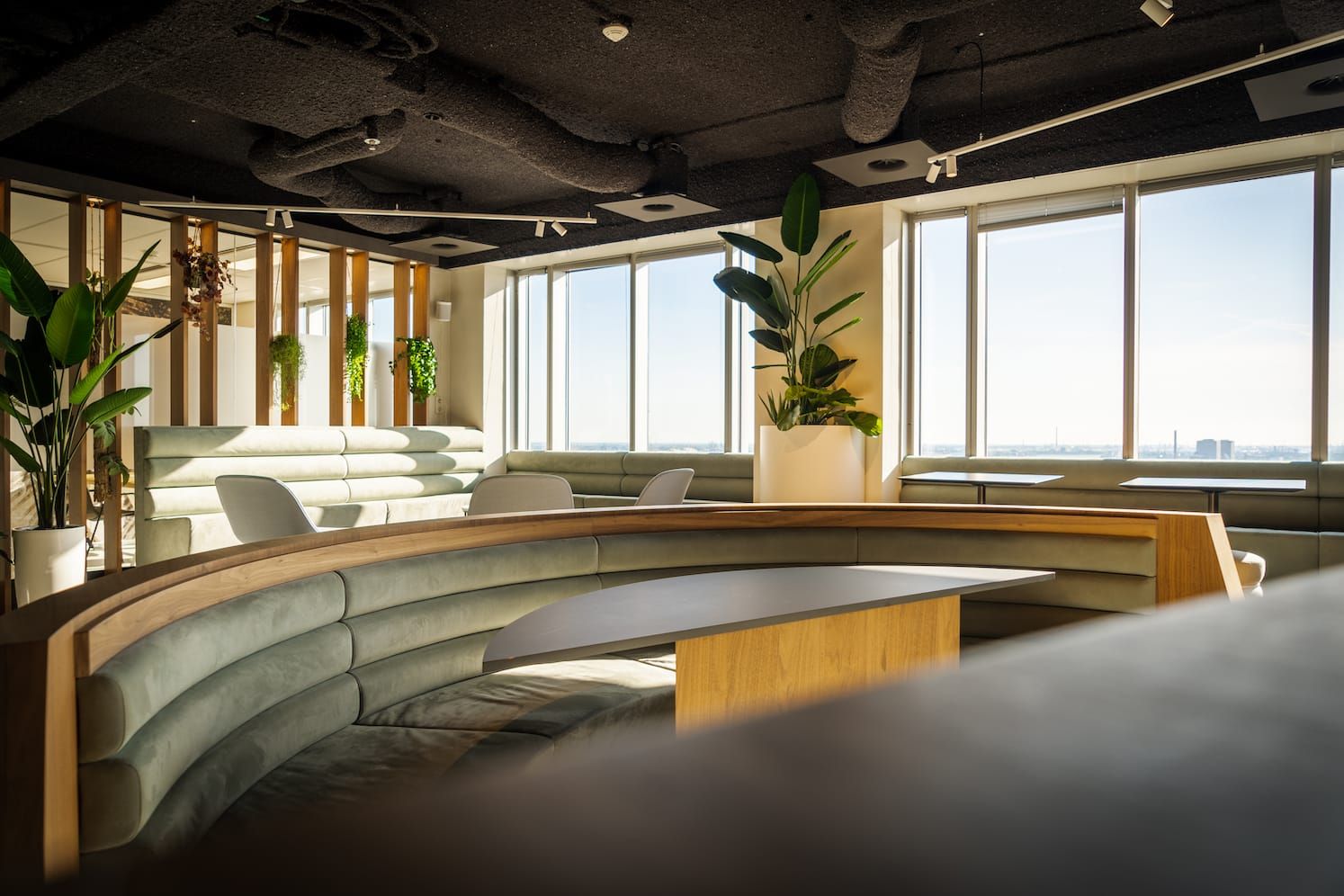 Semicircular pale green booth with a wooden-based table facing the windows