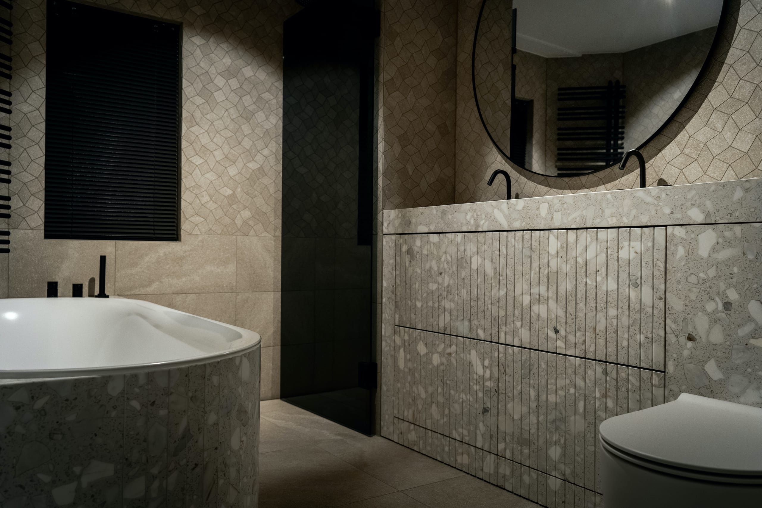 Riverslate bathroom with terrazzo bath surround, fluted vanity and round mirror