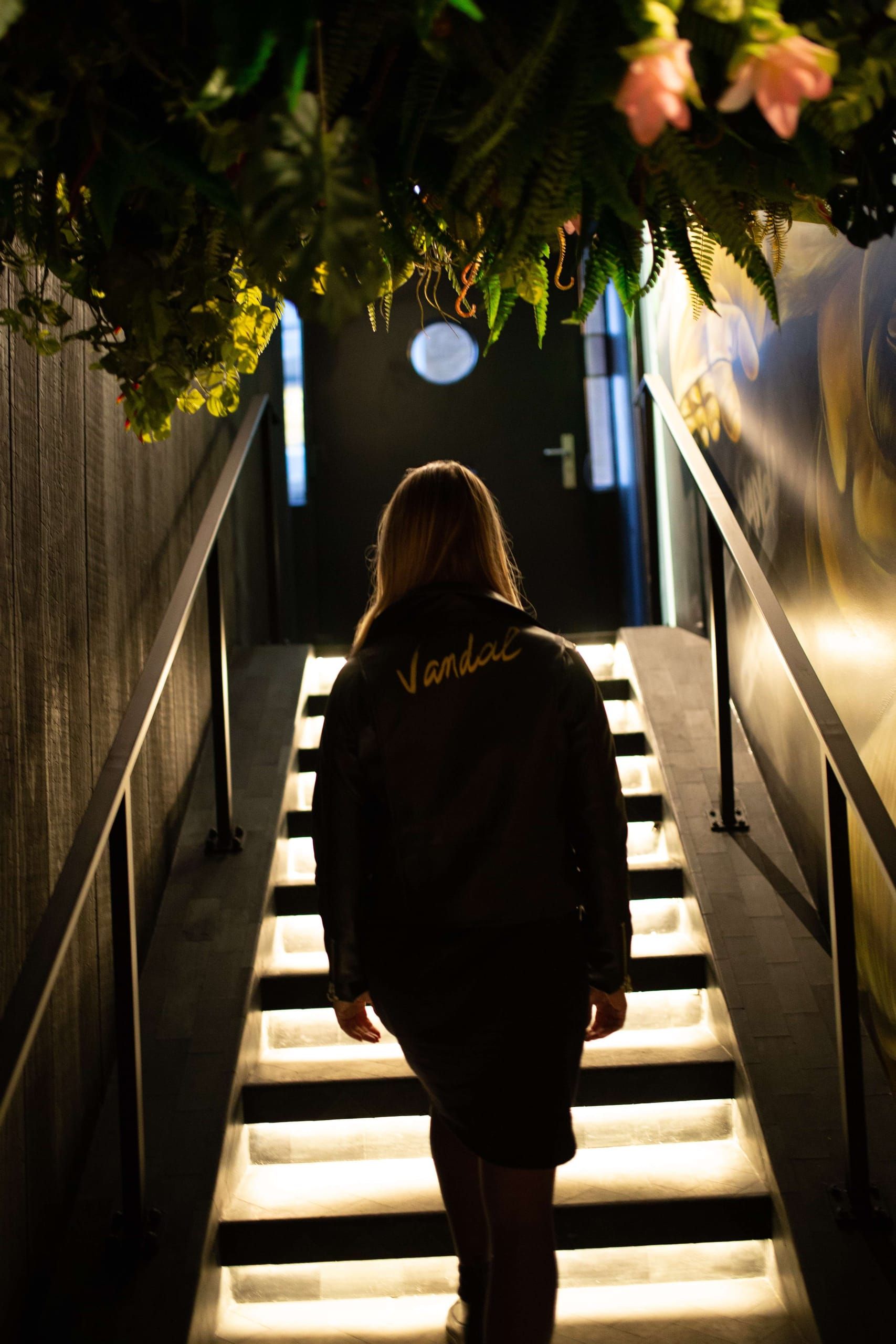 Lit stairs under hanging flowers and greenery leading up at Vandal