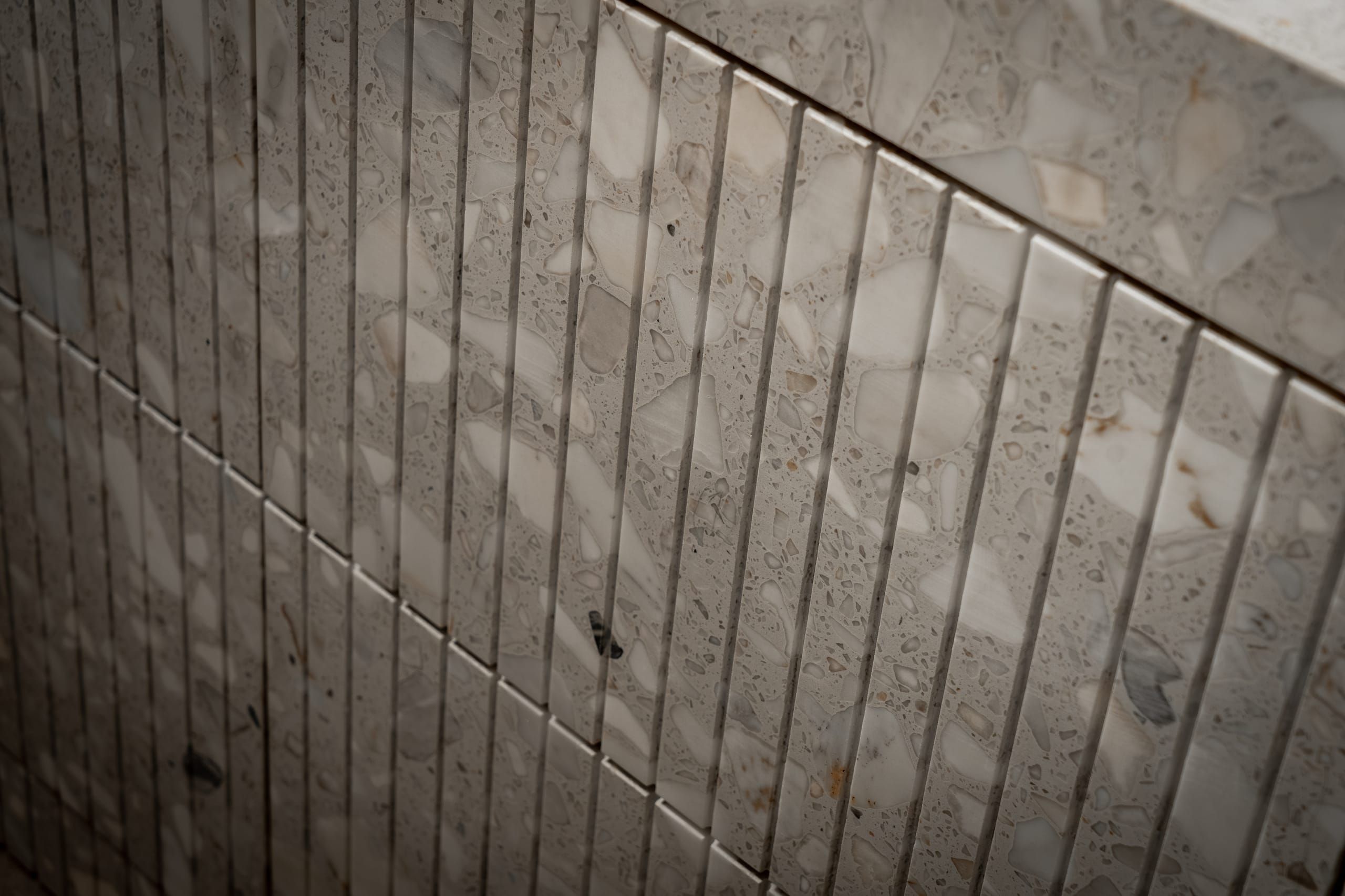 Vertical fluted terrazzo tiles clad in pale stone chips