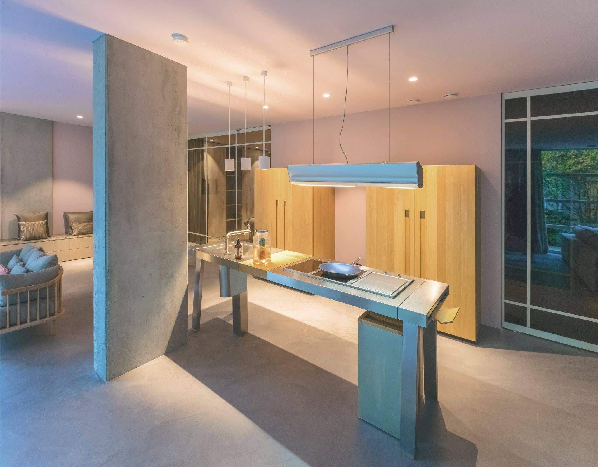 Steel kitchen island with pendant lights, concrete column and oak cabinets