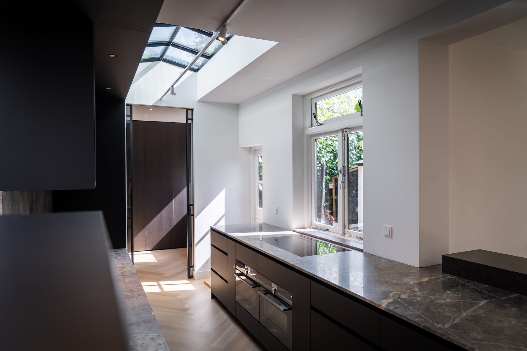 Kitchen with stone island, skylight and garden windows in daylight
