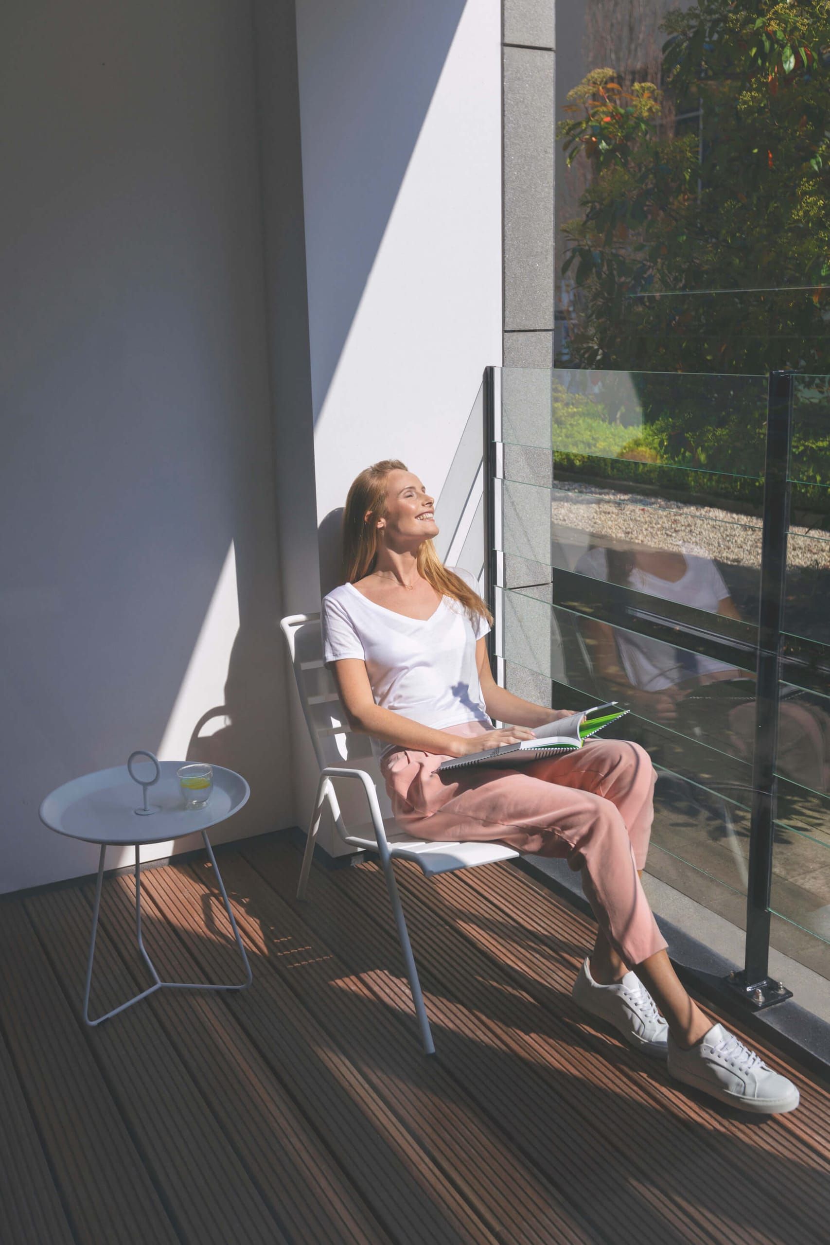 Sunlit balcony with white chair, side table and timber decking