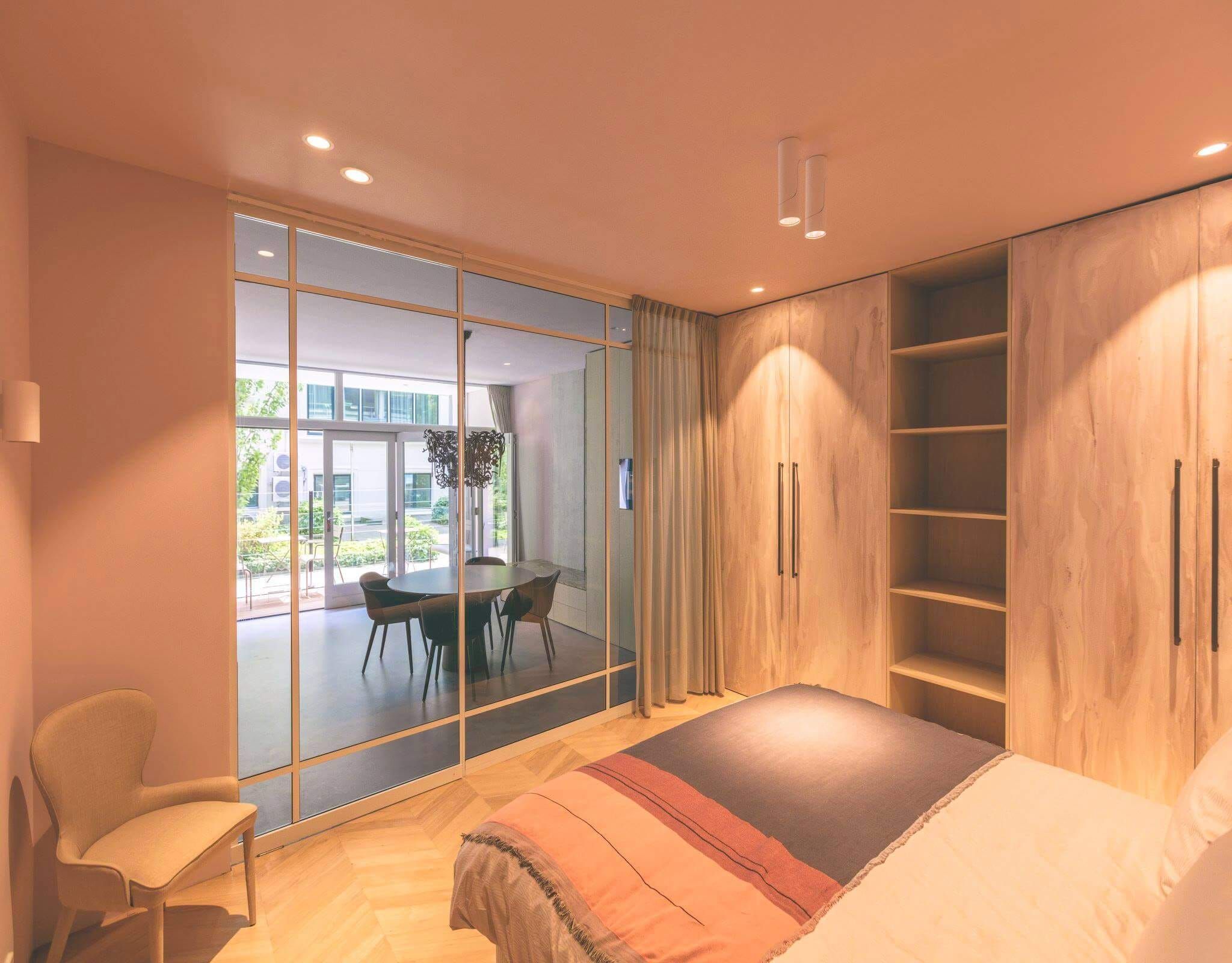 Bedroom with oak wardrobes, open shelving and a glass partition to the dining area
