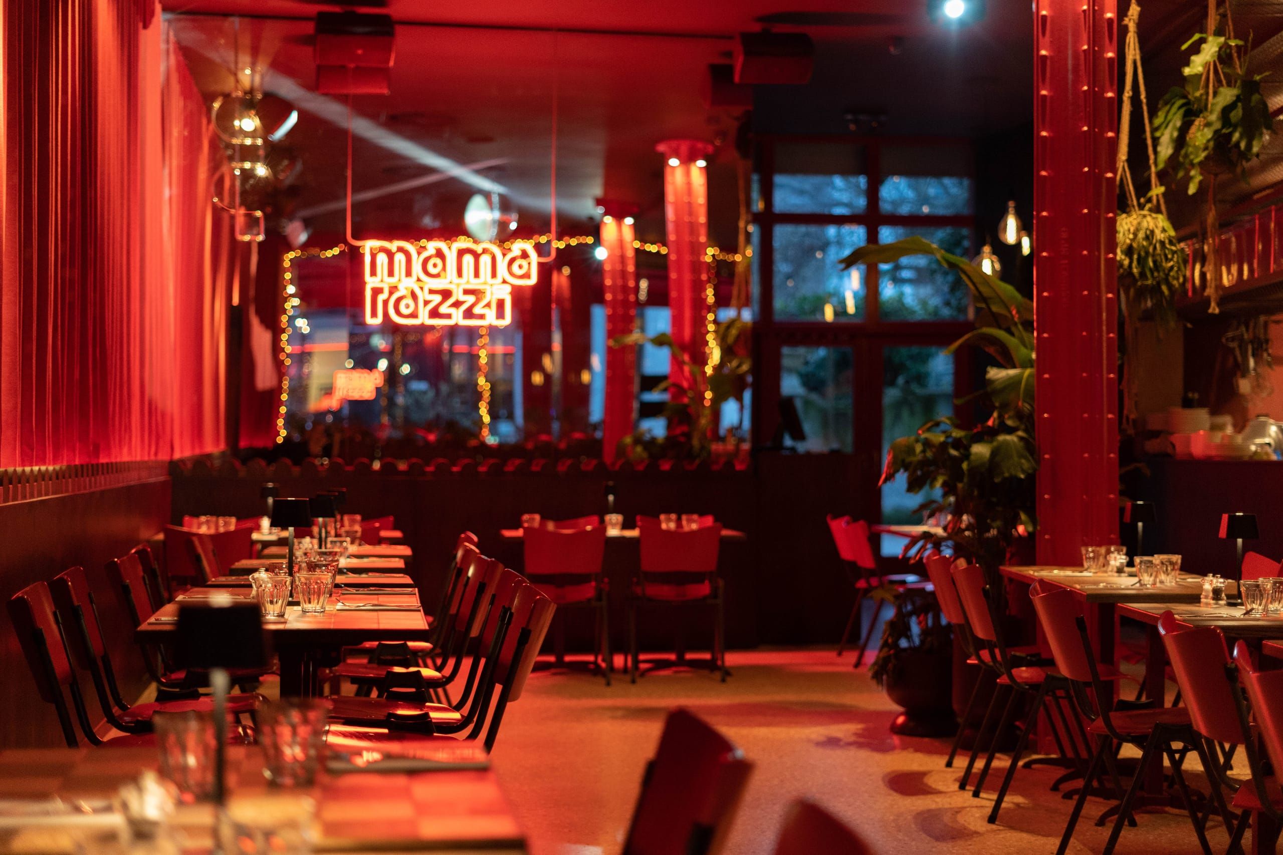Red dining room with neon Mamarazzi sign, curtains and glowing columns