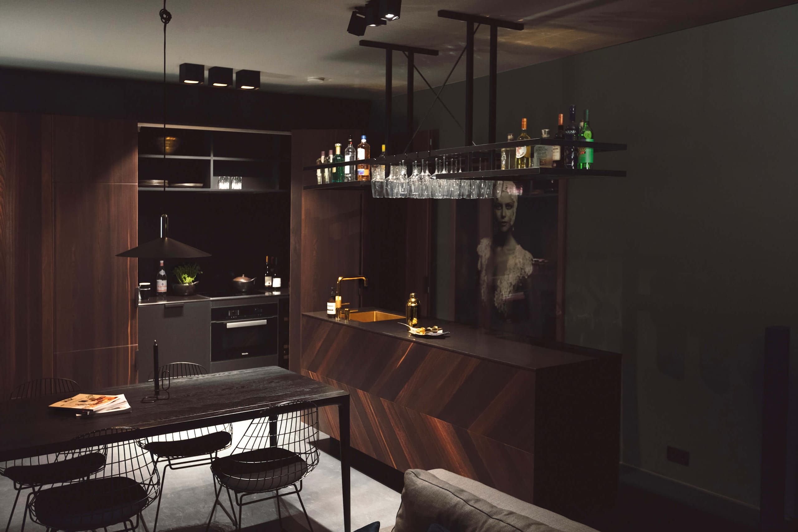 Moonlight kitchen with dark walnut island, hanging glass rack and black dining table
