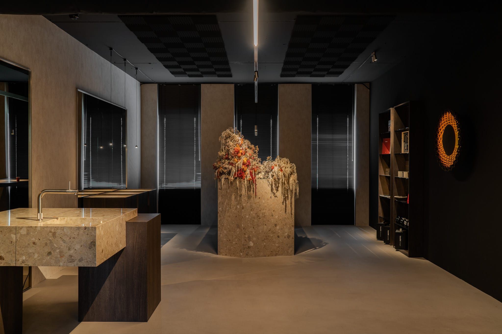 Showroom with a stone sink block, dried flower plinth and dark shelving in the TDG office